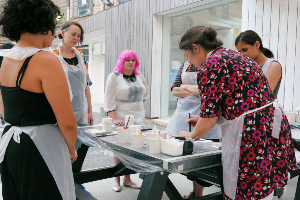 Artists gather round a demonstration of colour mixing