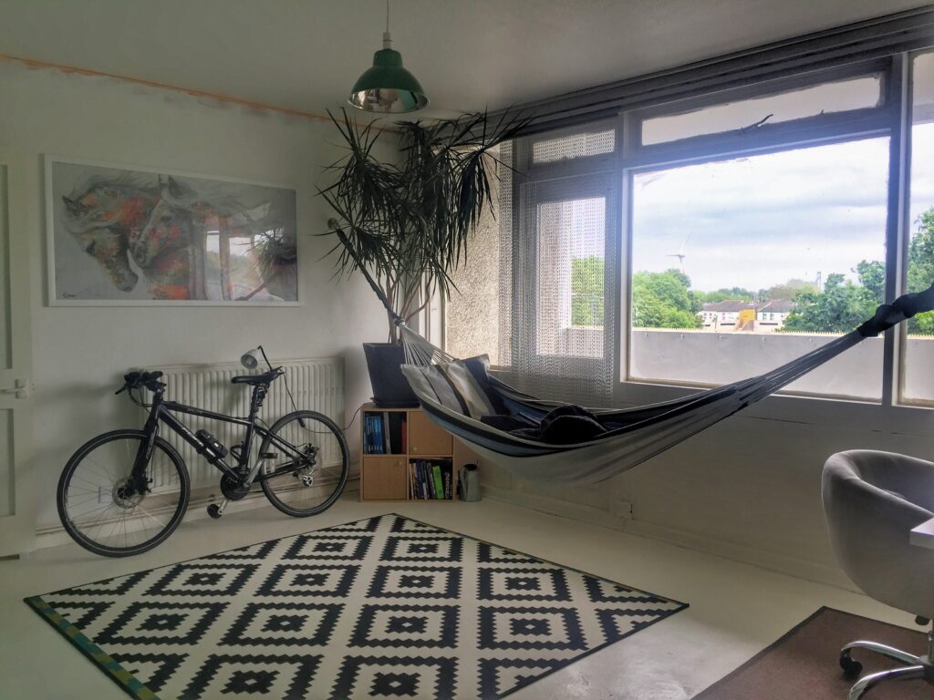 The reception room of a flat with a rug, bike and hammock