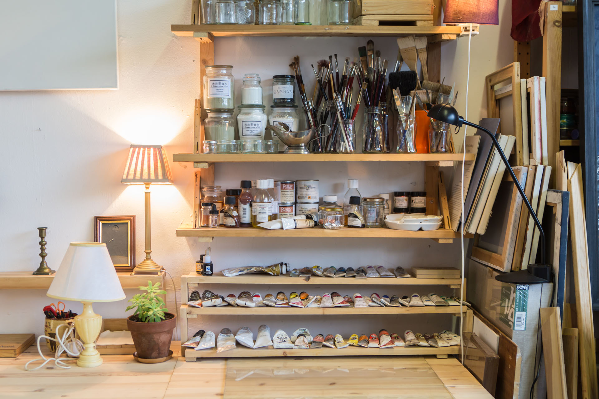 A desk with shelves holding paint and other artist tools