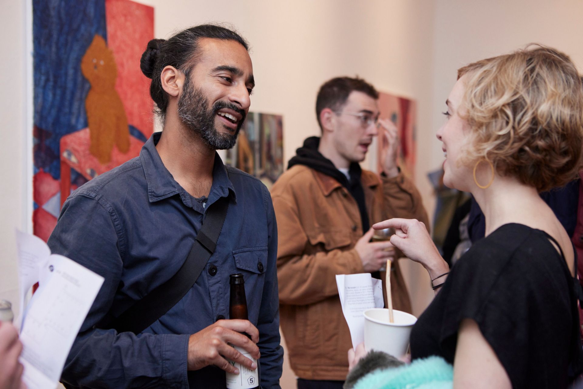 Two people talk with artwork behind them, in the Nunnery Gallery