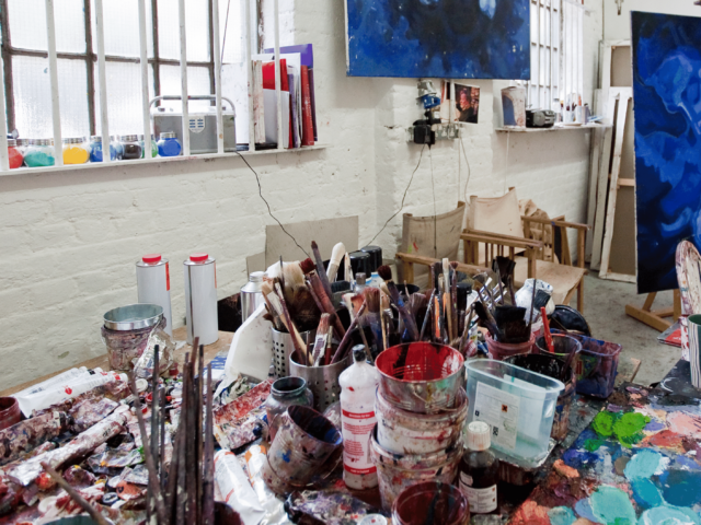 Paint and paintbrushes on a table in a Bow Road studio