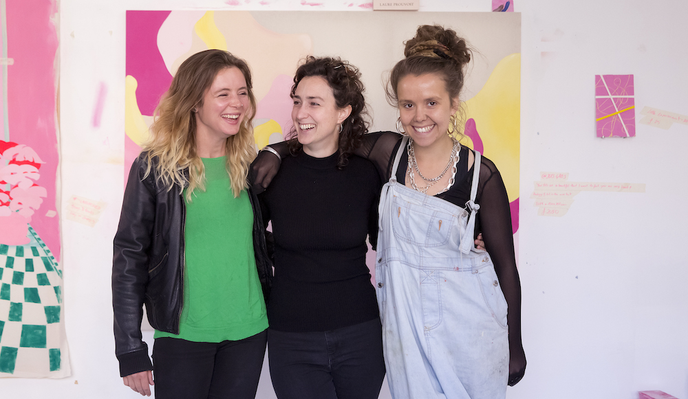 Group of artists loop arms in a studio