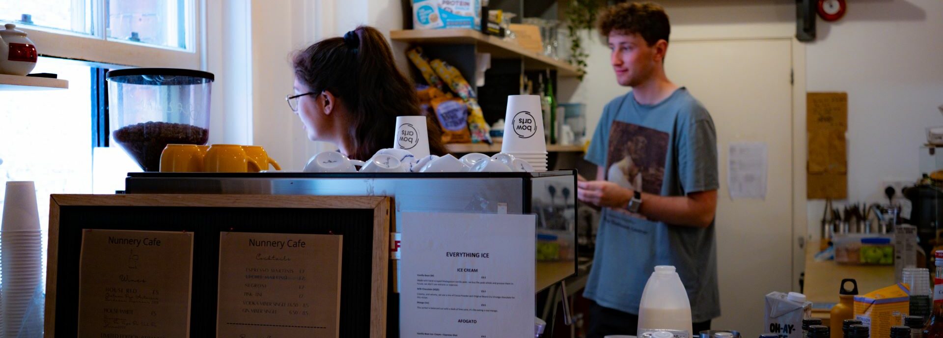 Two people serve coffee out of a window hatch