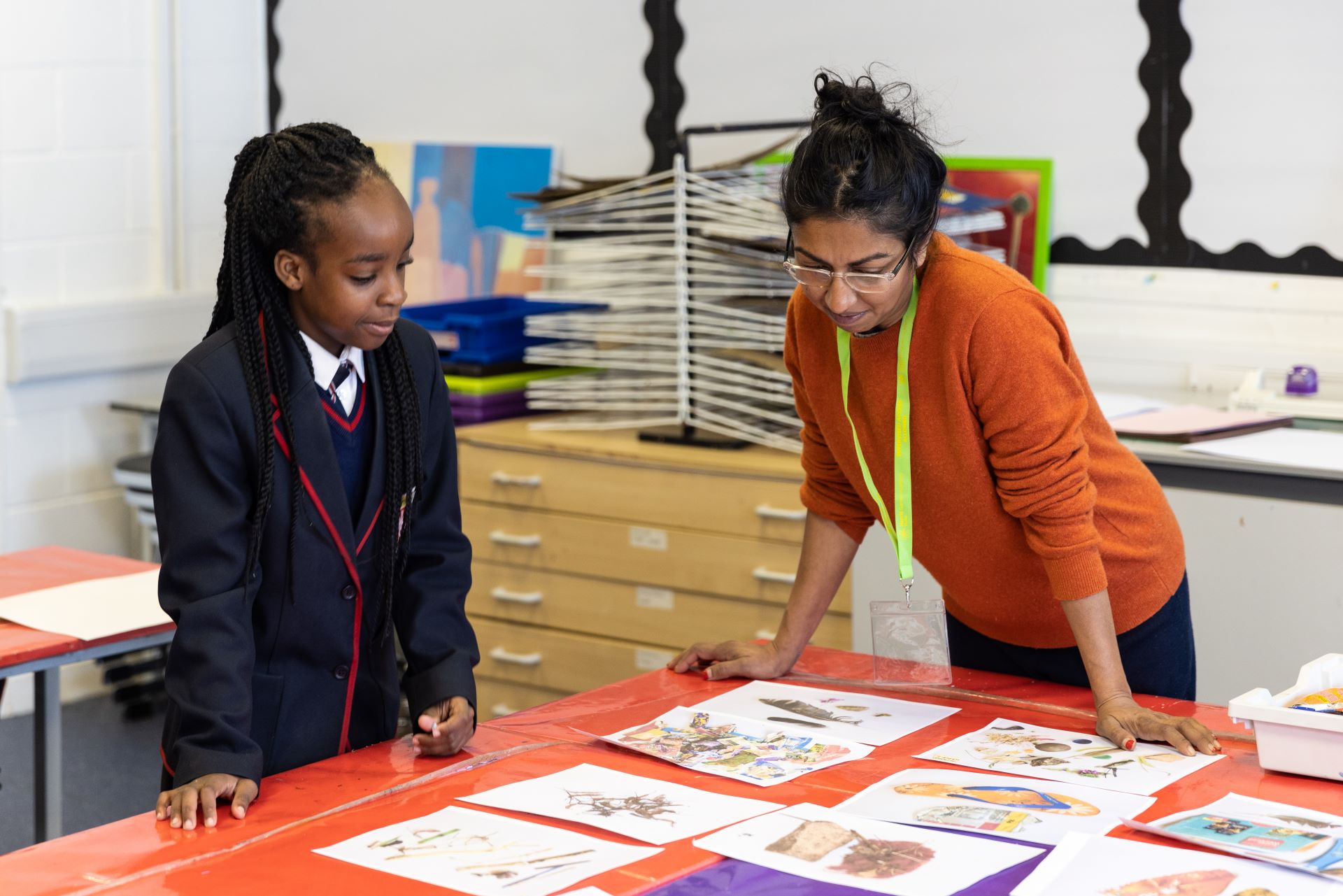 A pupil and artist educator look at drawings on a table