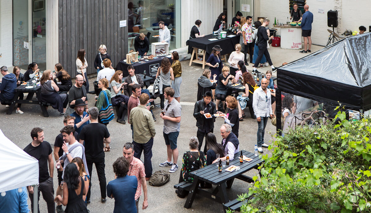People mingle in the Bow Arts courtyard, eating and drinking