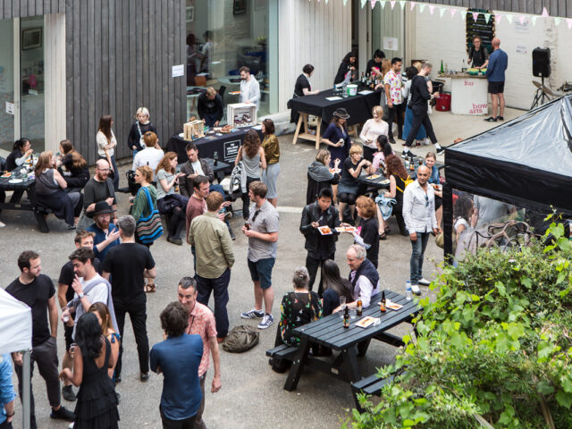People mingle in the Bow Arts courtyard, eating and drinking