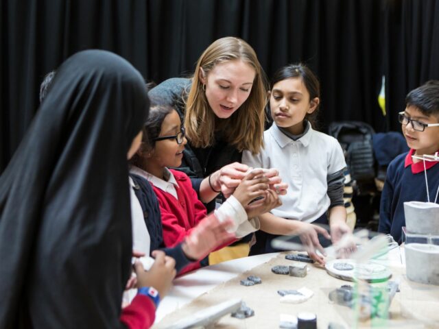 Pupils play with clay, helped by an artist educator.