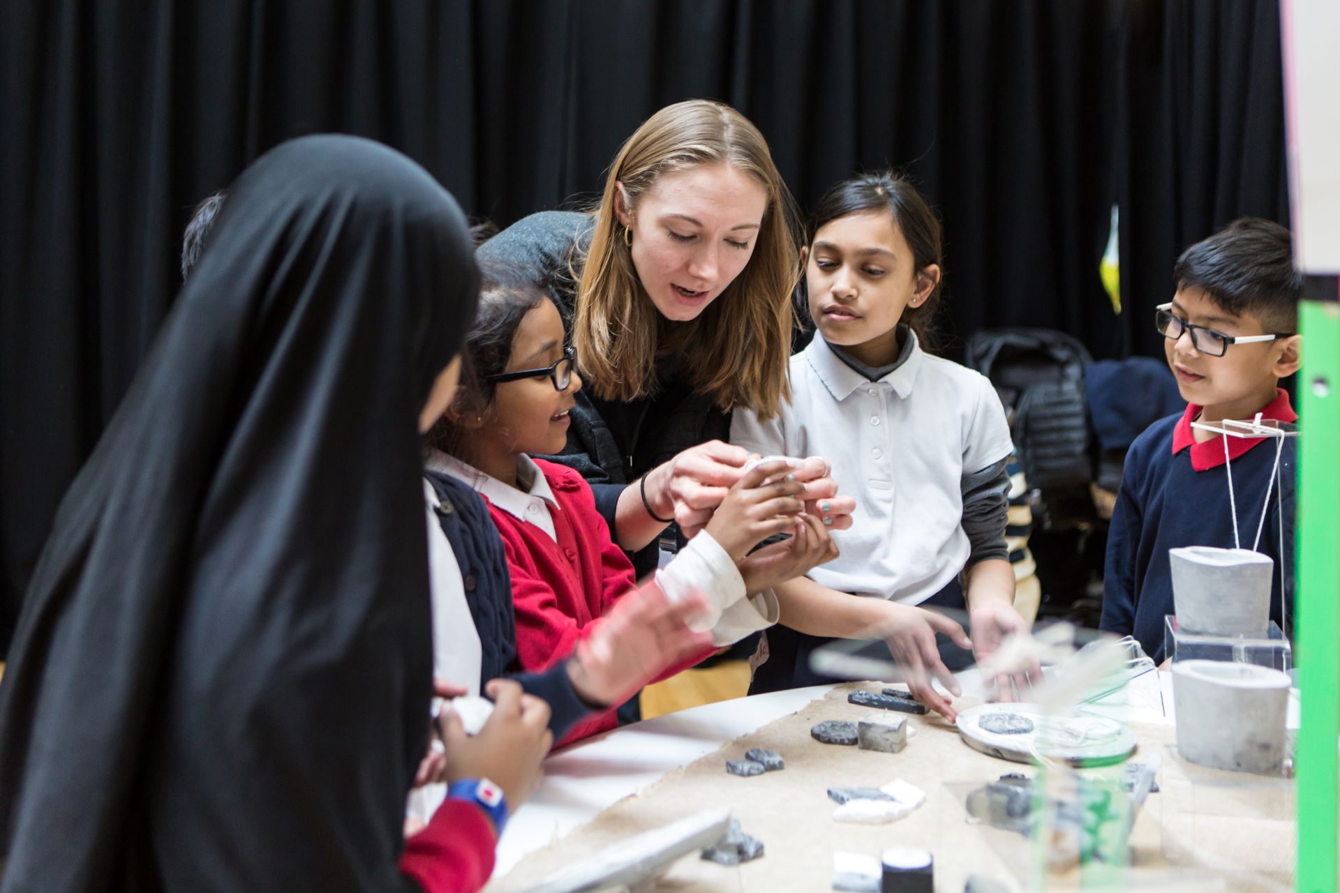 Pupils play with clay, helped by an artist educator.