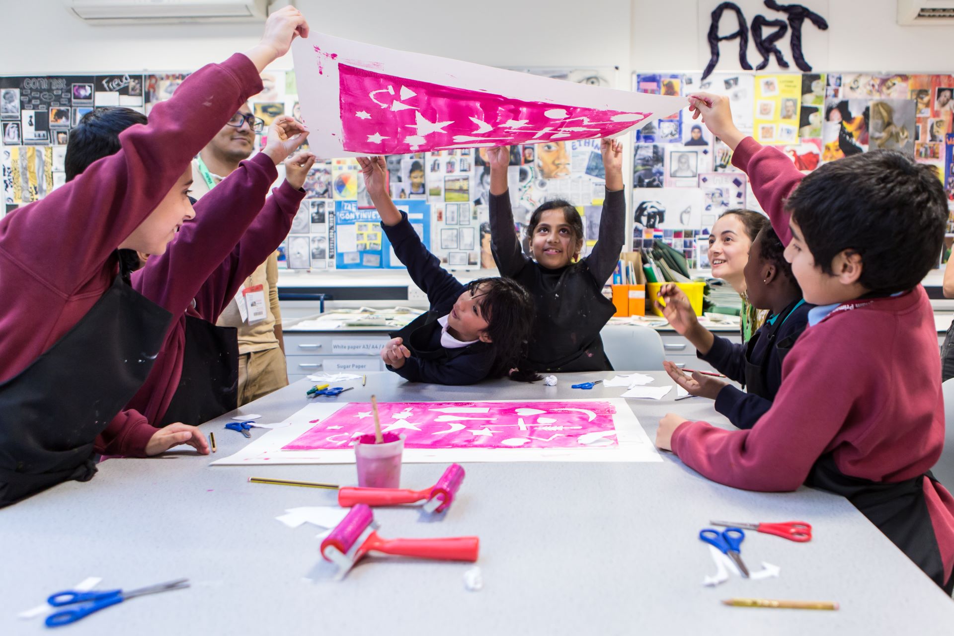 Children hold up their work and look at it from underneath