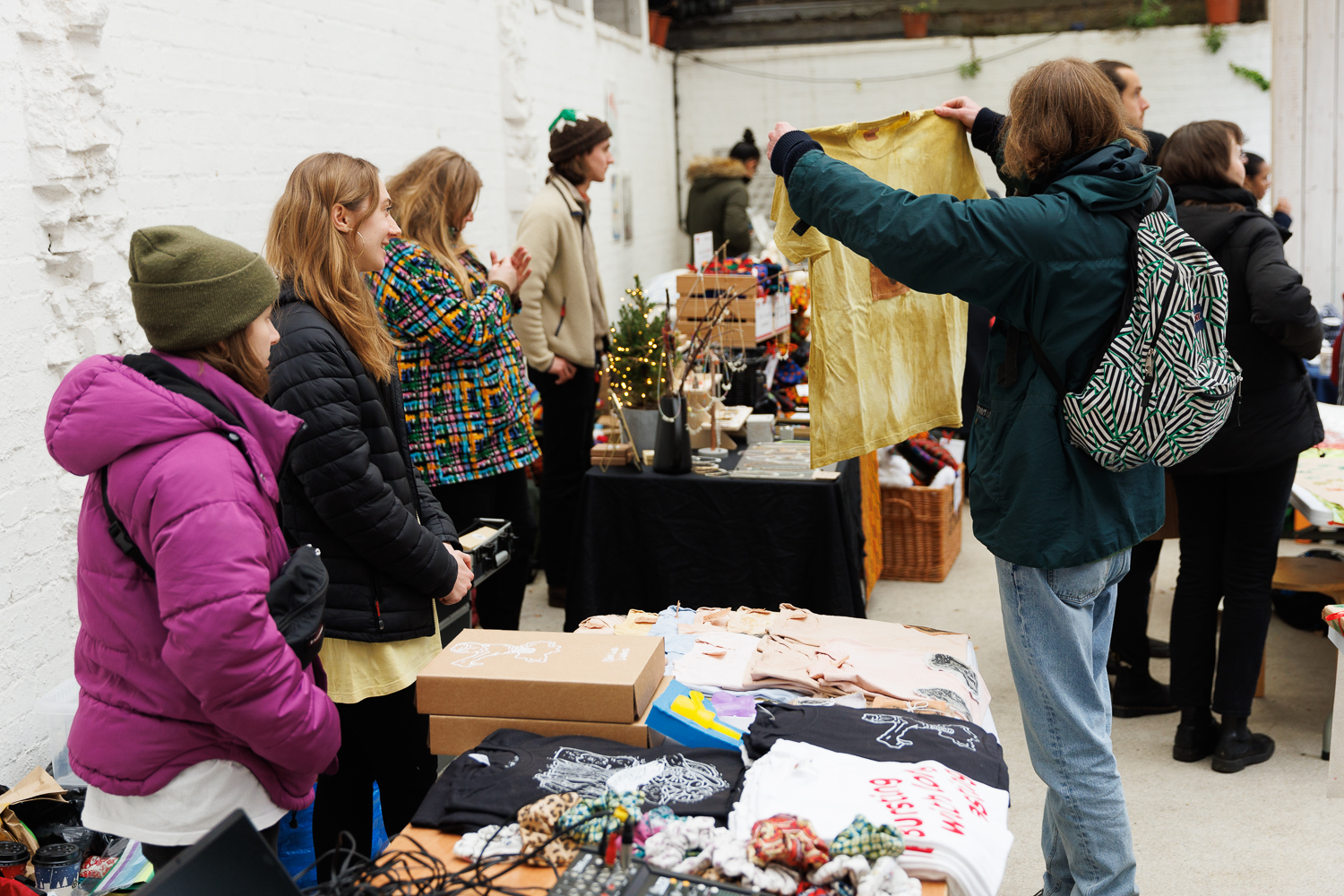 Someone holds up a tshirt at a stand while the stall holders look on