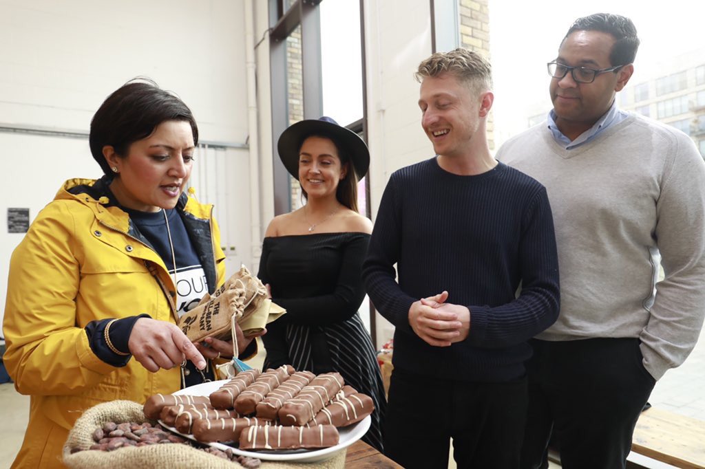 Four people stand around a plate of chocolate talking