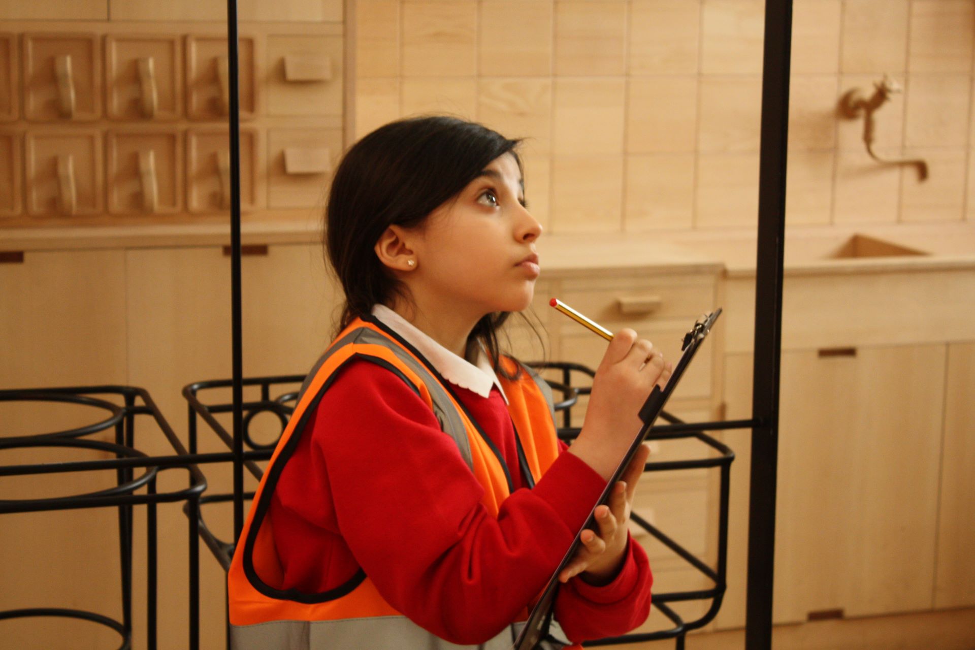 A child draws with a clipboard looking up