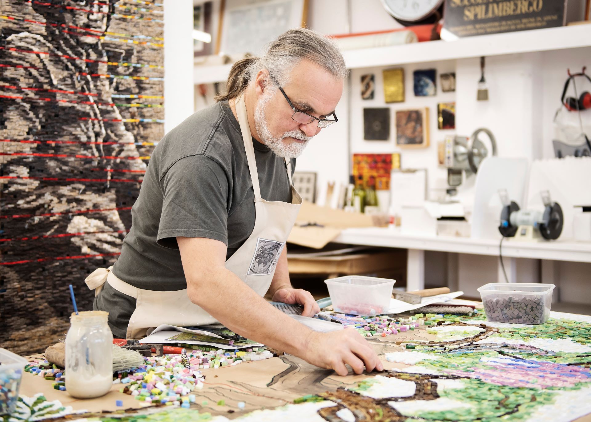 An artist lays mosaic pieces in their studio