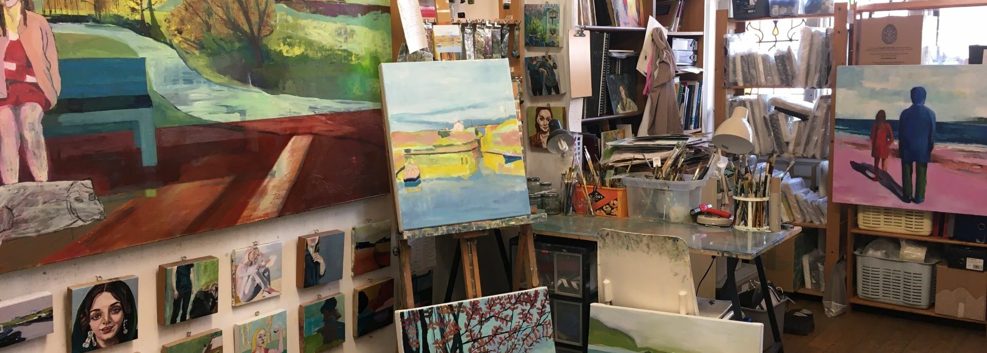 A studio with artwork hung up on the walls, an easel and other objects