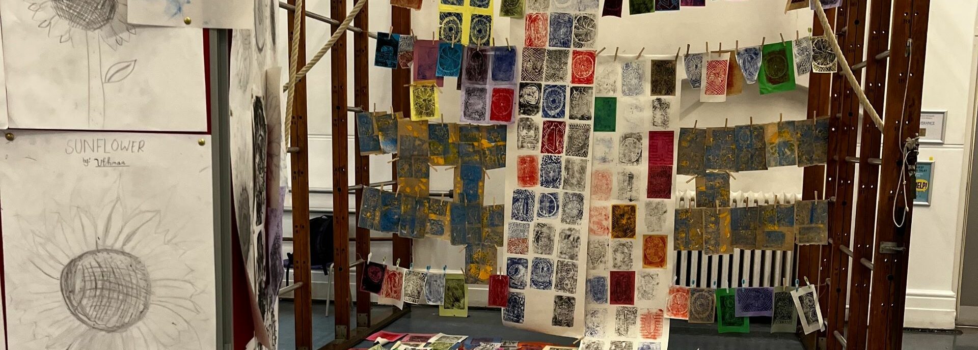 Colourful prints of fruit hanging up on a wooden apparatus