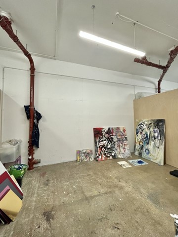 A studio with paintings leaning against the far corner