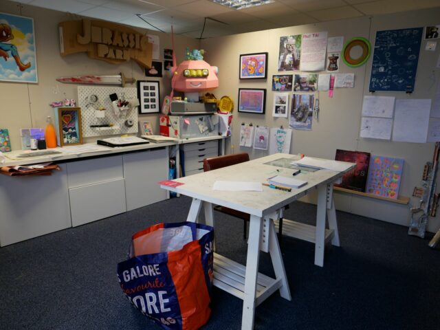 a studio with a table in the centre and artwork on the walls