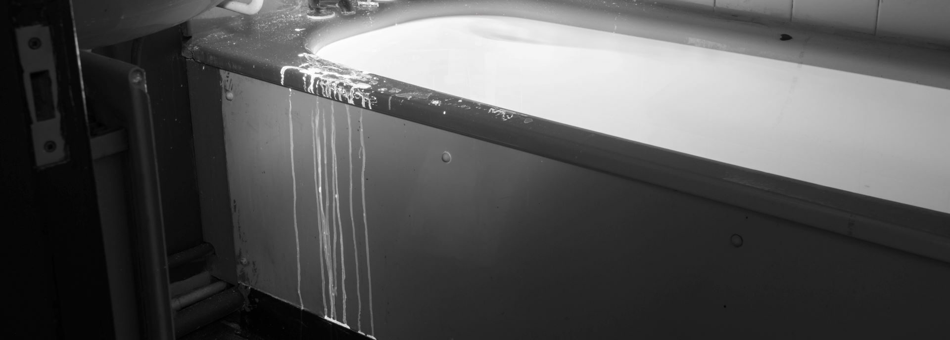 A monotone photograph of a bath, a white liquid drips down the side of the bath