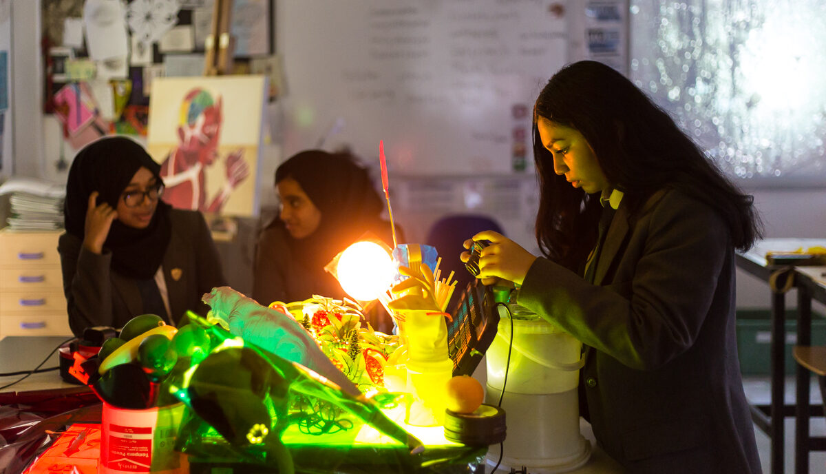 A student takes a photo of a lit up installation