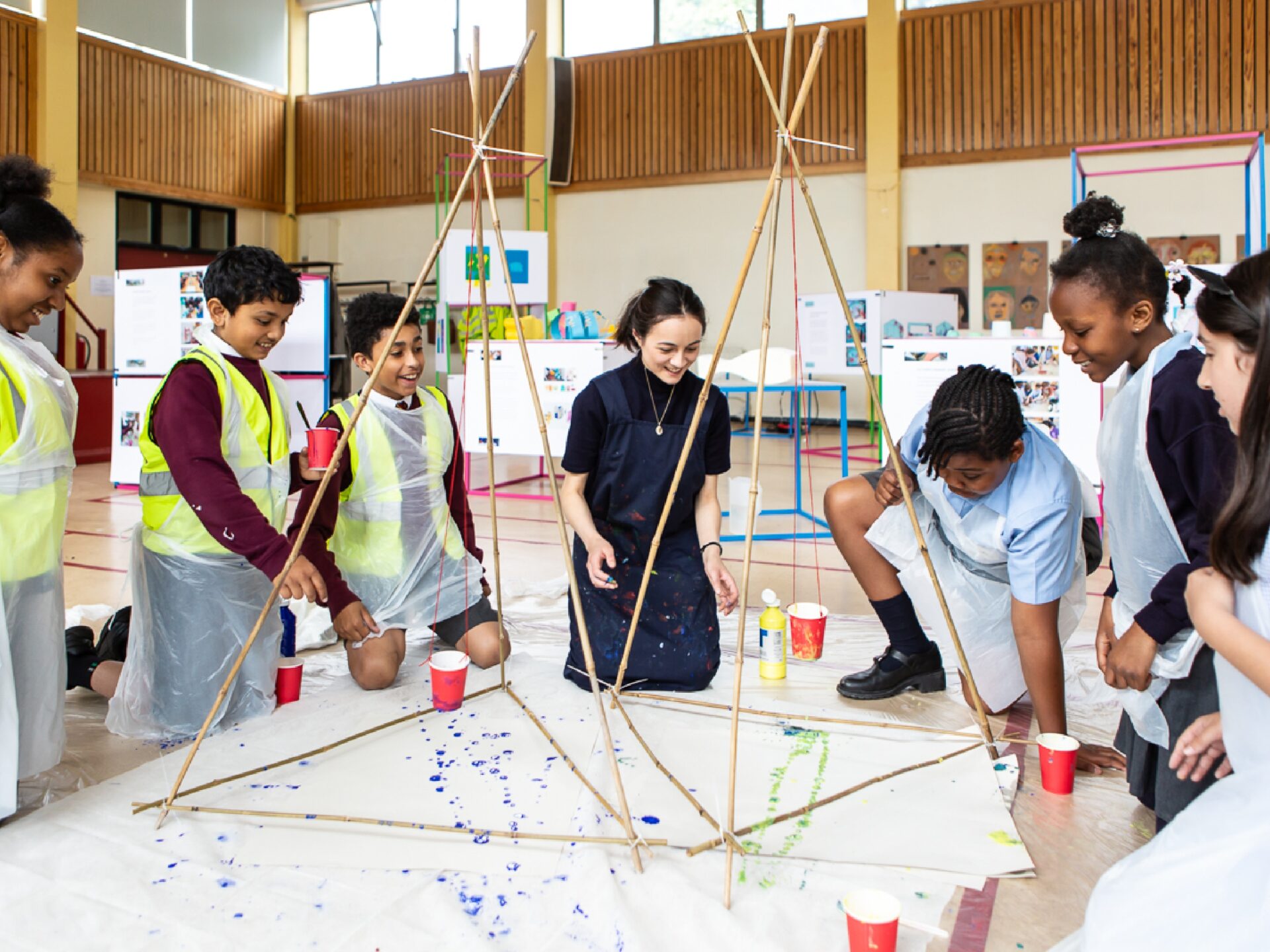 Students flick paint onto a sheet of paper on the floor