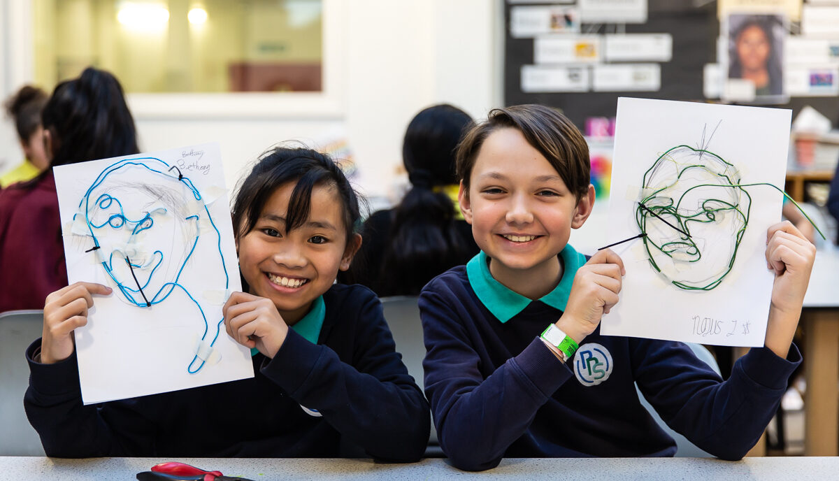 Students holds up wire self-portraits