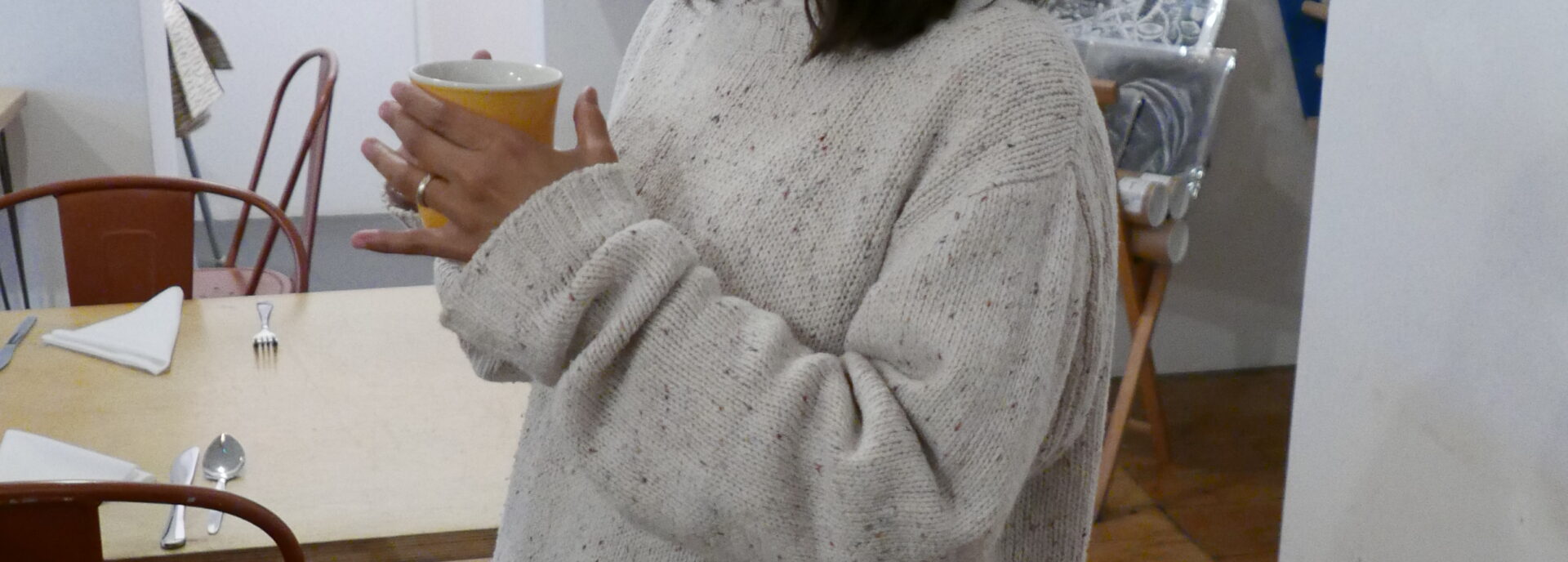 Maliha Haider smiles and holds a coffee in the Nunnery Café