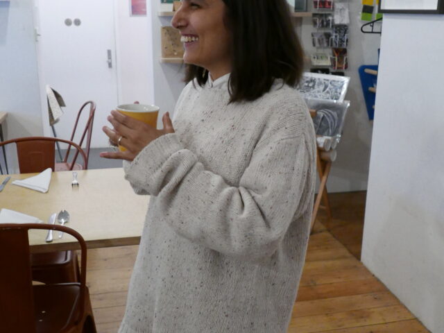 Maliha Haider smiles and holds a coffee in the Nunnery Café