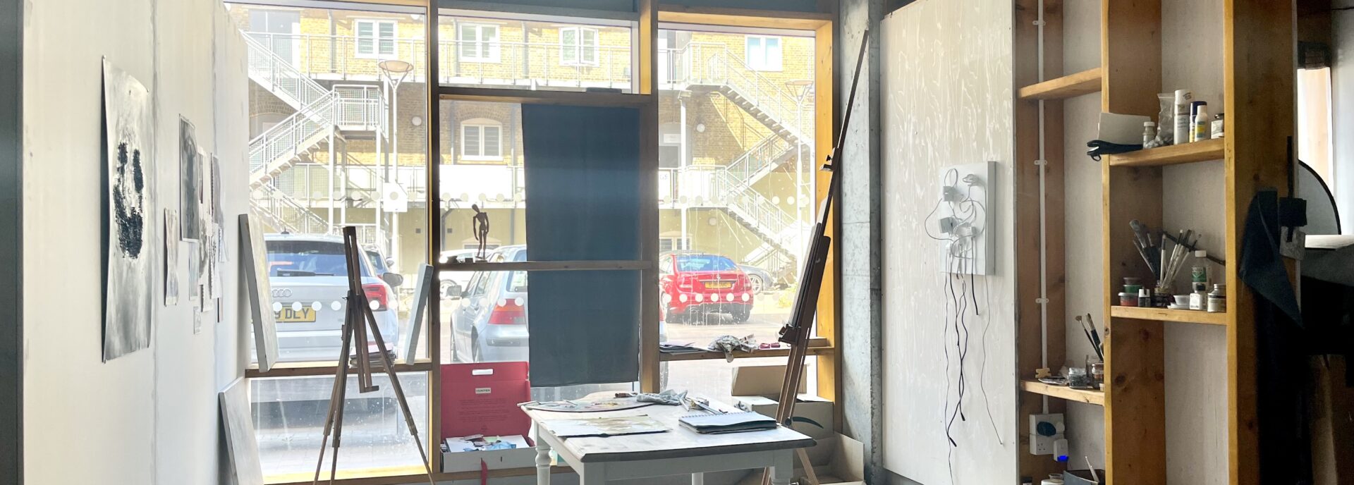 A studio with easels and a table and floor to ceiling windows