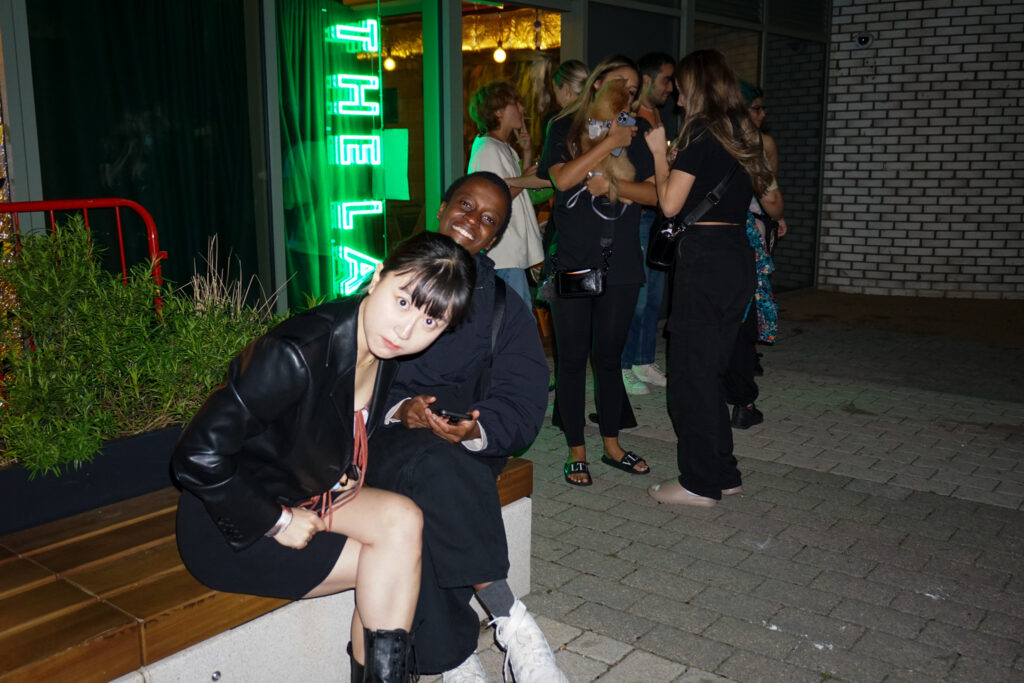 People sitting outside infront of a neon sign which reads The Lab