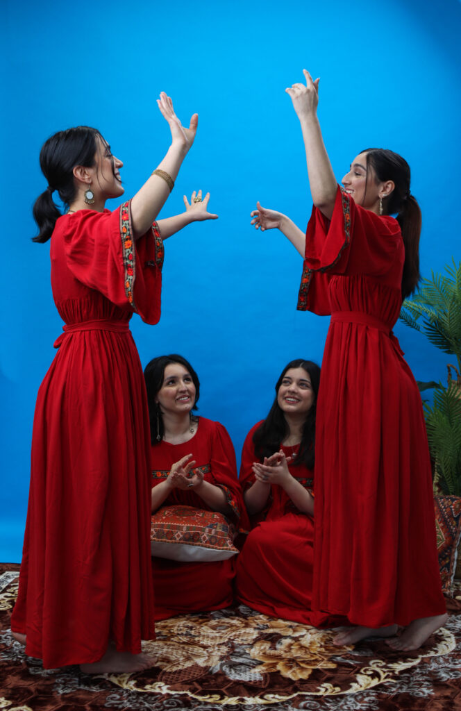 Four young women in red Afghan clothing on a rug.