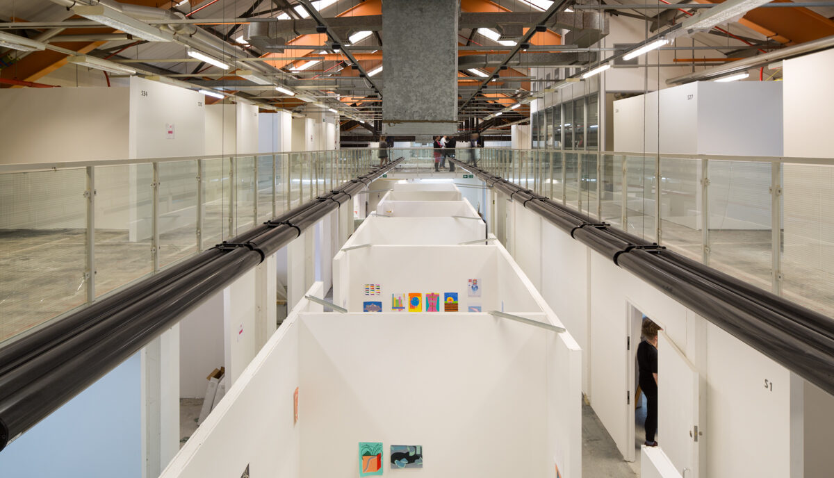 View from a mezzanine looking out over a long building with multiple partitioned art studios