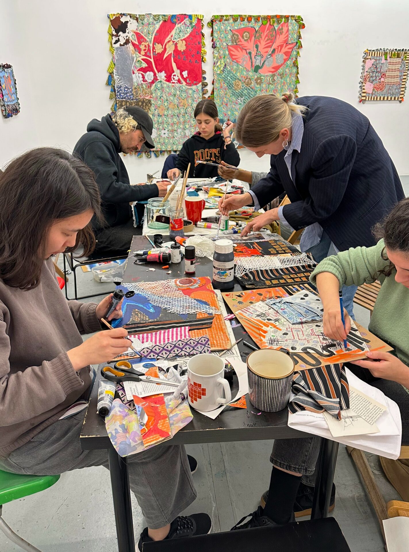 people of all ages gatehred to paint and collage around a table