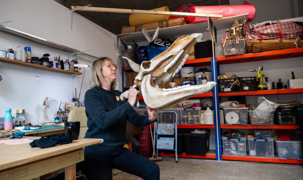 Charlie Tymms poses in her studio with a puppet skull