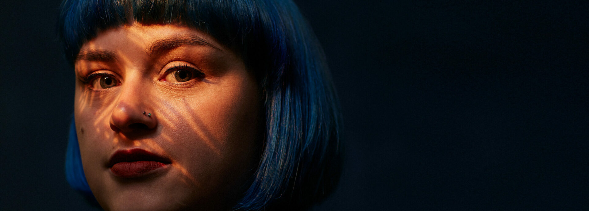 A white woman with blue hair in a ray of sun