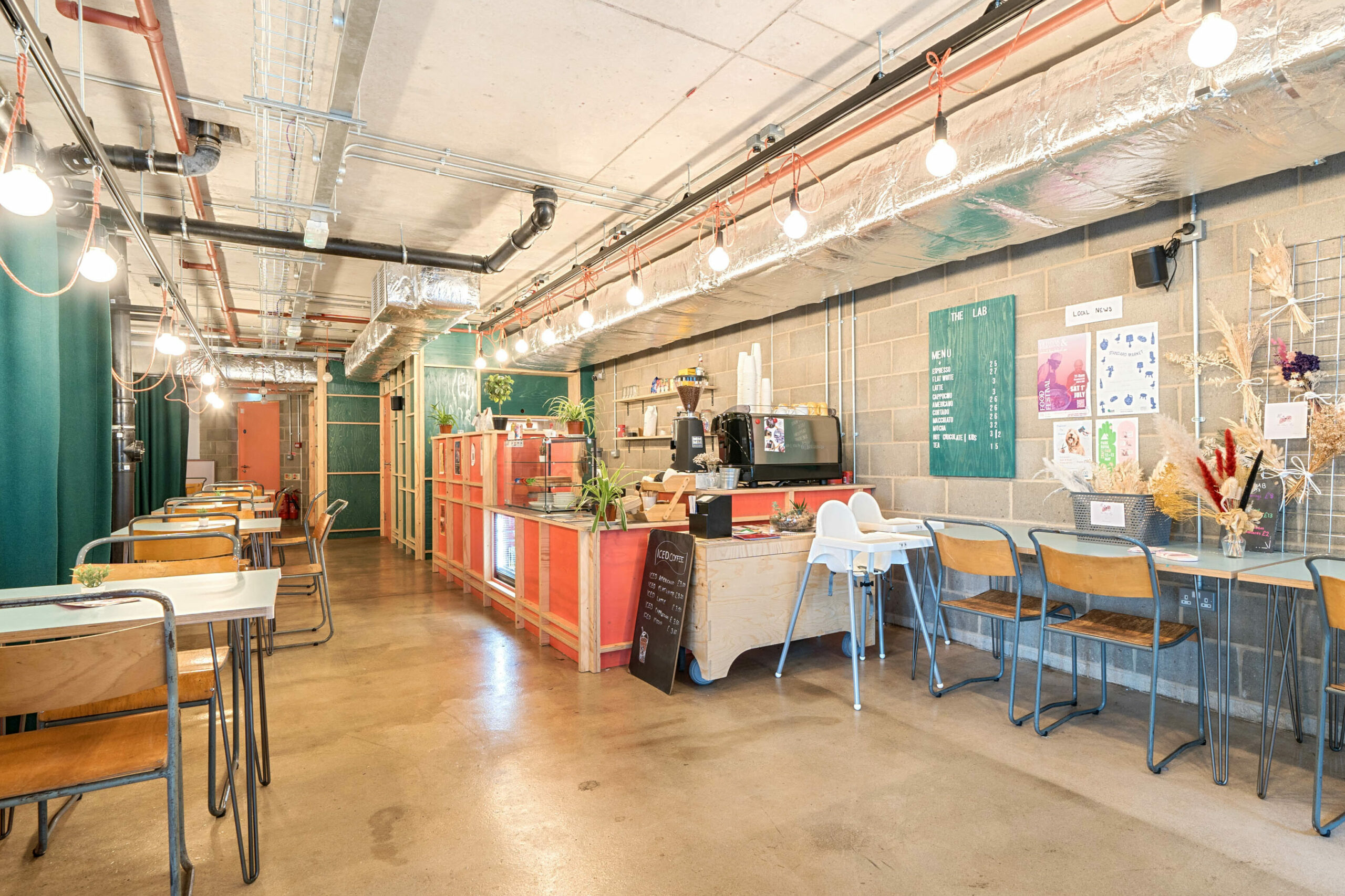  A warm red, blue, and wood toned café area, includes a few tables and chairs and main bar.   