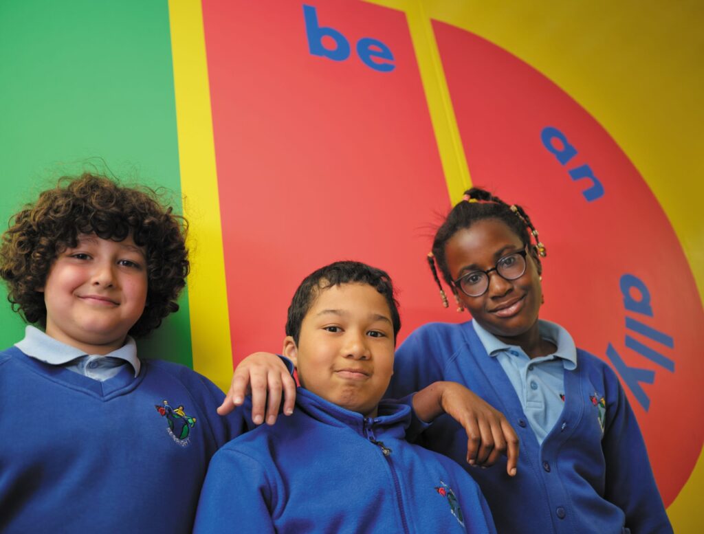 Three children in front of a mural