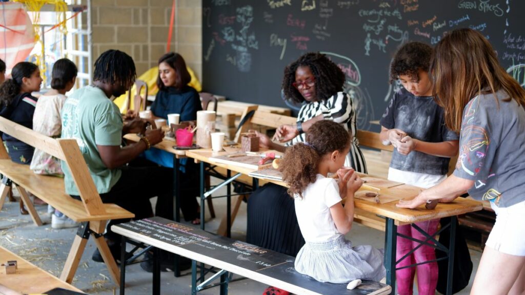 children and adults sit around a long table making art