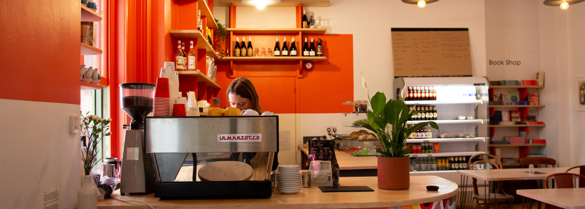 cafe interior with person making a coffee on a coffee machine.