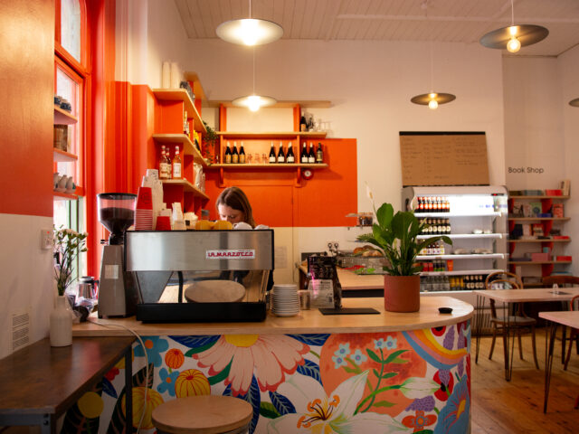 cafe interior with person making a coffee on a coffee machine.